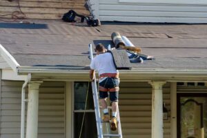 Workers inspect attic insulation beneath a newly replaced residential roof during a cold-weather renovation.