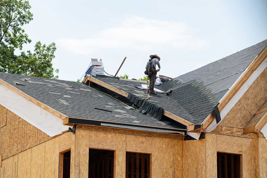 Inspector reviews roof assembly labels and fire-rating documents beside a residential attic access panel.